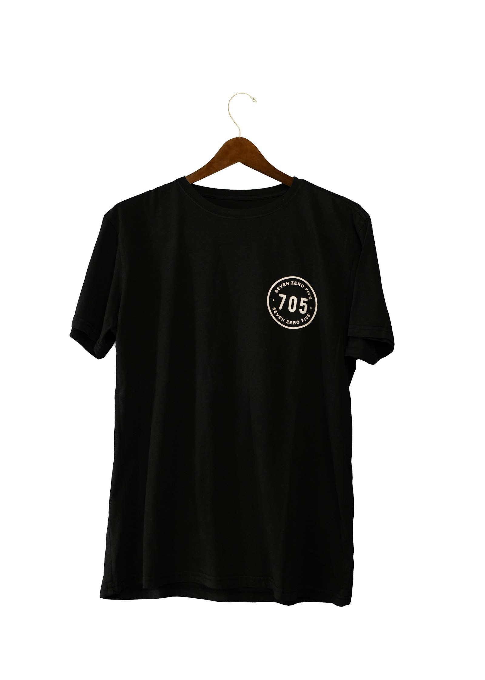A black t-shirt hanging against a white wall in directional light