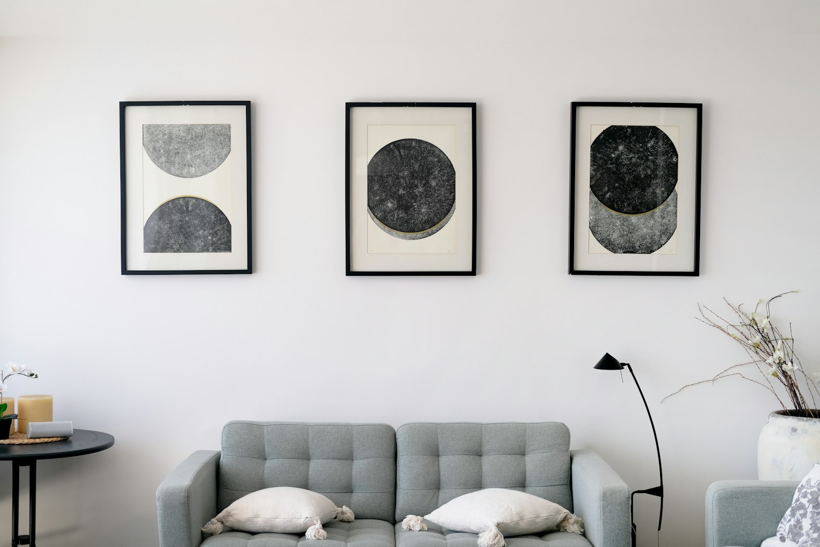 Three framed abstract prints hanging above a light grey sofa