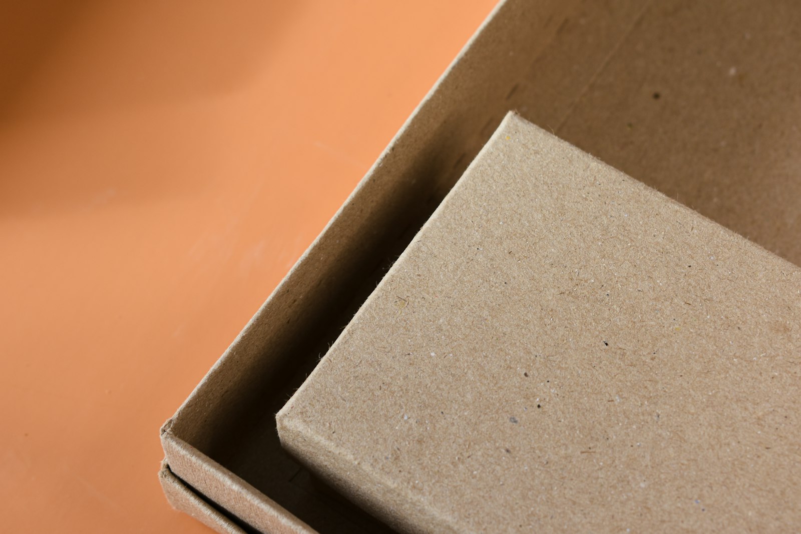 A minimal kraft packaging box photographed close up on a warm surface